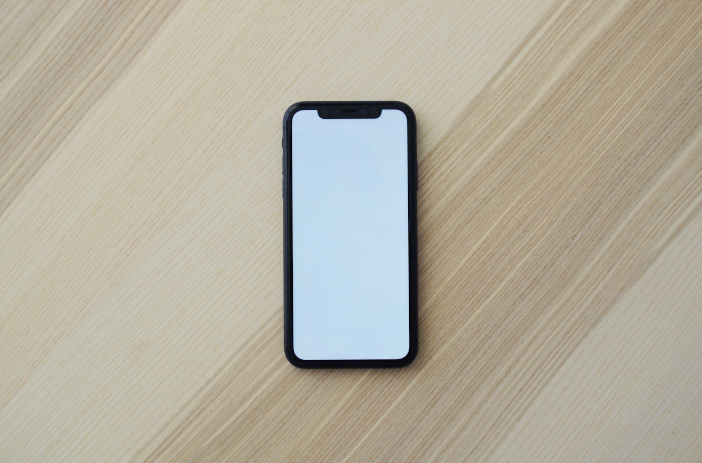 A smartphone lying face up on a light wooden table